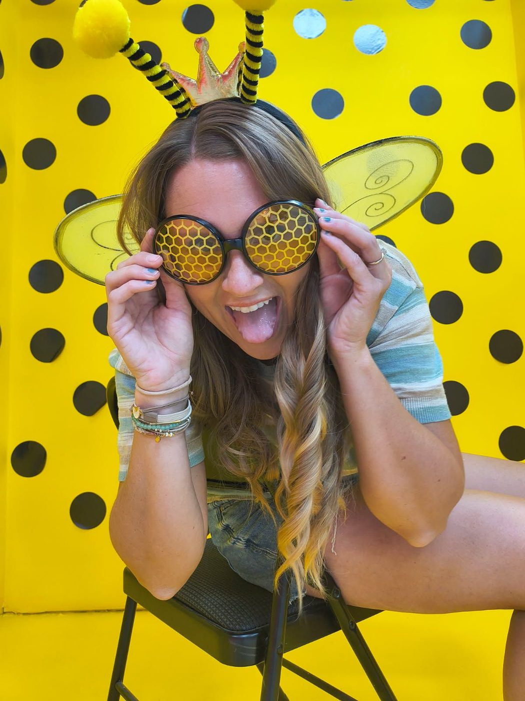 Guest in oversized sunglasses in front of the bumblebee black-and-yellow polka dot backdrop