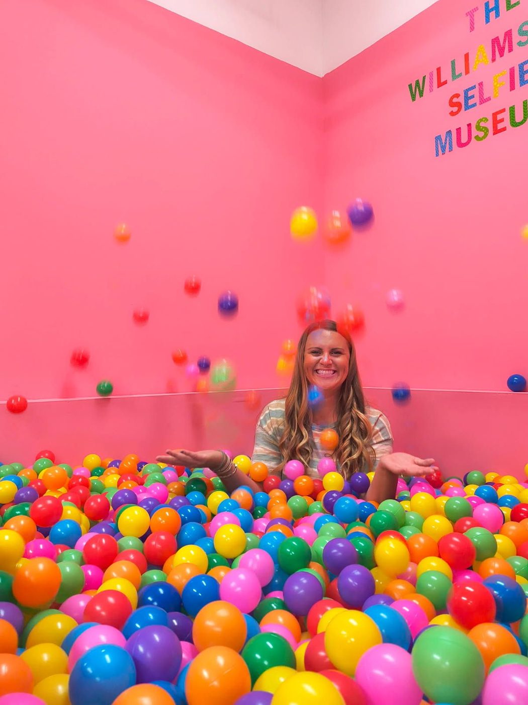 Guest in the rainbow ball pit at The Williamsburg Selfie Museum